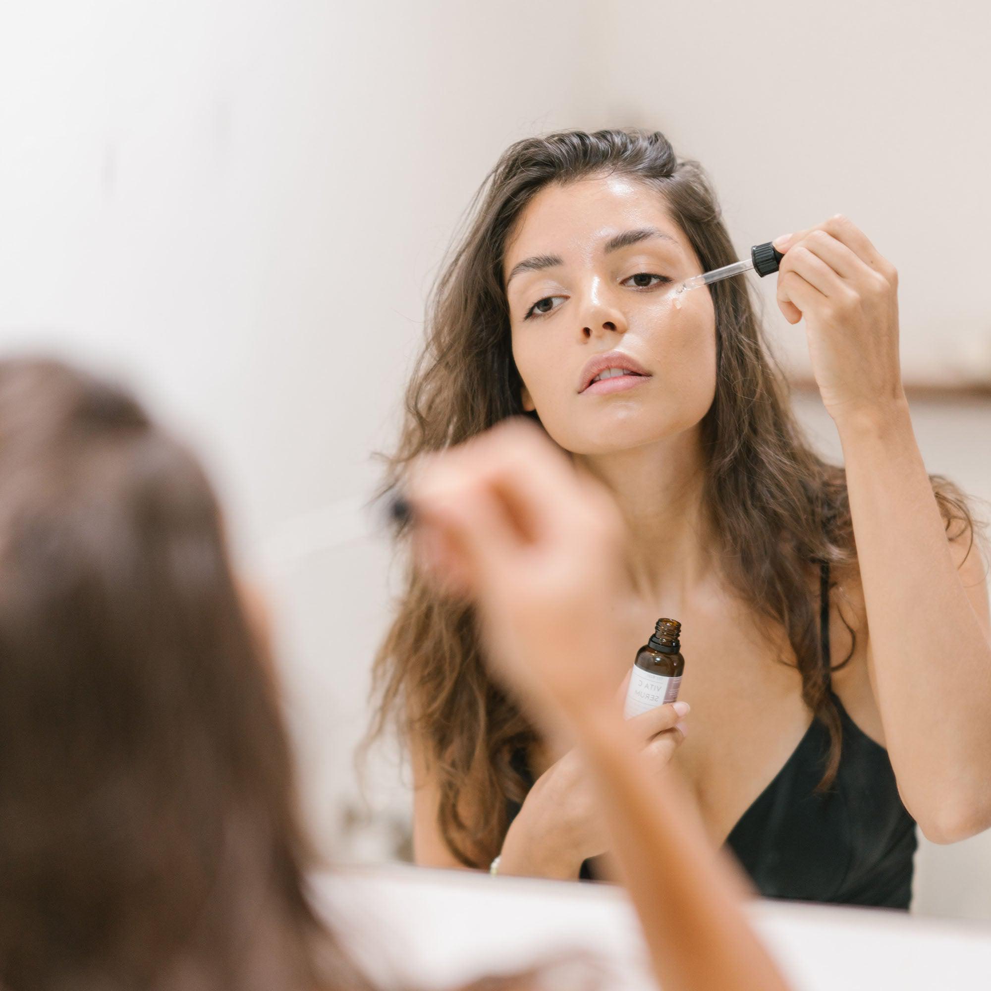 Een vrouw brengt een druppelaar aan op haar gezicht met het Nia Glow Serum.